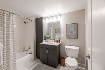 A bathroom with a white toilet, a sink, and a bathtub with a shower curtain